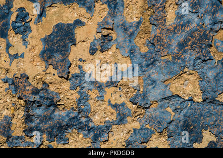 Yellow stone wall with dark blue paint pealing off/grunge wall texture background Stock Photo