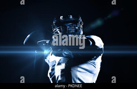 american football player throwing rugby ball against black background Stock Photo