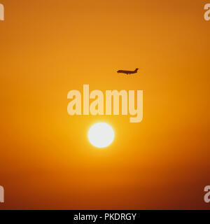 Passenger jet in sky at sunrise Stock Photo