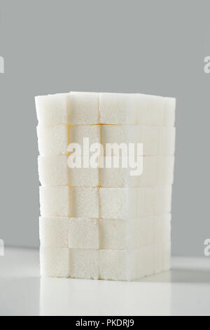 a pile of white sugar cubes, disposed in a block, on an off-white background Stock Photo