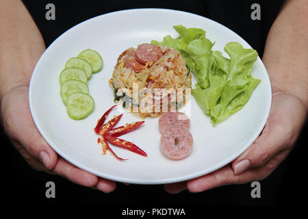 Thai traditional food, Fried  jasmine rice with Thai sour sausage topped cucumber, kale and green oat. Stock Photo