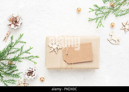 Kraft paper Christmas gift with empty tag on white background. New Year's decorations. Winter holiday composition, mockup. Stock Photo