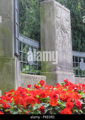 Close-up of a stone monolith & red begonias in the Royal Scots War Memorial inscribed with battles through the ages;  Princes St Gardens, Edinburgh Stock Photo