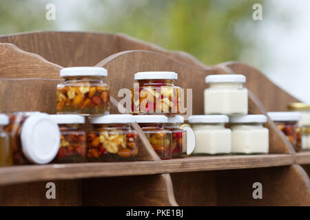 Nuts and honey in small jars on shelf Stock Photo