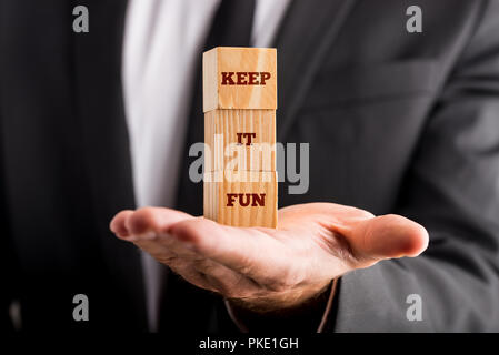 Businessman holding three wooden cubes vertically aligned, with  Keep it fun sign, concept of dynamism, fun and positive atmosphere. Stock Photo