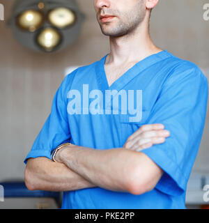 Close-up portrait of doctor surgeon in blue clothes on background of the operating lights. Stock Photo