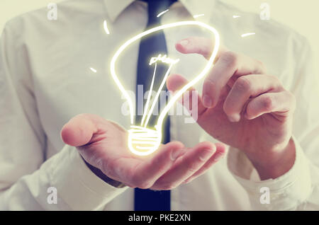 Retro image of businessman holding a creative light bulb icon in his hands conceptual of ideas, inspiration, imagination, and innovation. Stock Photo