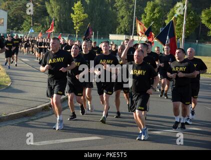 Members of U.S. Army Garrison Bavaria participate in a large formation run during physical training time in Grafenwoehr, Germany, July 25, 2018.  The run was the first team-building event since U.S. Army Europe realigned its 3 combat brigades under the mission command of the 7th Army Training Command. Stock Photo