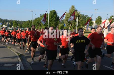 U.S. Soldiers from the 2nd Cavalry Regiment participate in a team-building run during morning physical training in Grafenwoehr, Germany, July 25, 2018.  Several thousand U.S. Soldiers stationed in Germany and Italy participated in the run, which was the first team event since U.S. Army Europe realigned its combat brigades under the mission command authority of the 7th Army Training Command. Stock Photo