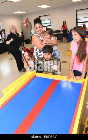Daniel Castanon, 5, takes turn throwing skeetball with his sister Mia, 10, while their mother Marie and sister Lexi, 1, watches. The Castanon Family joined other Fort Drum community members at the Army Community Service building July 26 during the ACS Birthday celebration. ( Stock Photo