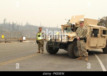 Sgt. Jesus Valencia and Spc. Cameron Hodges of the California Army National Guard’s 270th Military Police Company, 185th Military Police Battalion, 49th Military Police Brigade, secure a checkpoint July 29 at the Keswick Dam in Redding, California, shortly after the Carr Fire passed through the area. Stock Photo