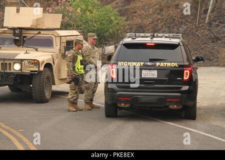 Military police from the California Army National Guard supported law enforcement late July in Redding, California, after the Carr Fire erupted and destroyed 500 structures and torched nearly 50,000 acres within a week. Sgt. Jesus Valencia and Spc. Cameron Hodges of Cal Guard’s 270th Military Police Company, 185th Military Police Battalion, 49th Military Police Brigade, update a California Highway Patrol at Redding’s Keswick Dam. Stock Photo