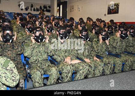 LAKES, Ill. (July 27, 2018) Naval ROTC midshipman candidates check the seals of M50 gas masks in the USS Chief Recruit Fire Fighter Trainer at Recruit Training Command (RTC). The classroom training in the USS Chief was part of chemical, biological and radiological (CBR) defense education for the new incoming midshipmen during indoctrination to the Navy. More than 65 young men and women entering their freshman year of the NROTC program participated in a two-week pilot program designed to provide standardized entry-level militarization and prepare midshipmen with a common training orientation. T Stock Photo