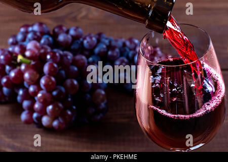 Bottle and glass of red wine, grape and cork on wooden background Stock Photo