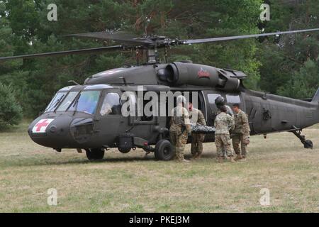 CAMP GRAYLING, Mich.- Soldiers from the 134th Medical Company (Ground Ambulance), Iowa Army National Guard, load a notional patient into a UH-60 Blackhawk helicopter during Northern Strike 2018 at Camp Grayling, Mich., on Aug. 7, 2018. The 134th MC is training with Company C, 1st Battalion, 168th Aviation Regiment, Colorado Army National Guard to enhance their medical evacuation and patient treatment skills. Stock Photo