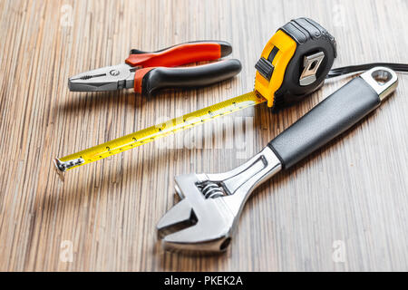 Adjustable pliers, Wrench and measuring tape on wooden table background. Working tools Stock Photo