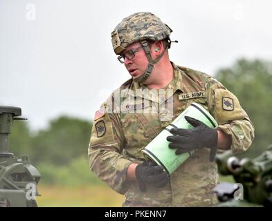 Sergeant Andrew Torres, a soldier assigned to Charlie Battery, 1st Battalion, 206th Field Artillery Regiment, 39th Infantry Brigade Combat Team, Arkansas National Guard, waits to hear instructions from the gun chief during the live fire training exercise at Fort Chaffee Joint Maneuver Training Center, Arkansas, July 28, 2018. Stock Photo