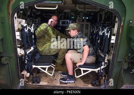 FORT BENNING, Ga. (July 30, 2018) – Australian army Sgt. 1st Class Ewan B. Jack, left, instructor, talks combat vehicles with 9-year-old Eli Wilson. Wilson visited locations throughout Fort Benning, Georgia, July 26. Wilson, who has Asperger’s syndrome, ate lunch at a dining facility with Delta Company, 1st Battalion, 46th Infantry Regiment, attended a basic training graduation, visited the National Infantry Museum, and met with the 316th Cavalry Brigade to see an M1126 Stryker Combat Vehicle and an M1 Abrams Main Battle Tank. Stock Photo