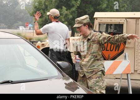 U.S. Army Pfc. Alaina Frees of the California Army National Guard’s 185th Military Police Battalion, 49th Military Police Brigade, helps a local resident entering Shasta College July 30 in Redding, California, where emergency services were set up to help victims of the Carr Fire. Stock Photo