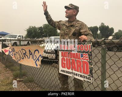 California Army National Guard’s Spc. Justin C. Piers of the 870th Military Police Company, 185th Military Police Battalion, 49th Military Police Brigade, responds to residents shouting “Thank You” as they pass the incident command post July 30 in Anderson, California, where the Cal Guard operates for the Carr Fire. The Redding, California, community and other Shasta County residents are constantly showing appreciation for Cal Guard troops who are running 12-hour shifts at traffic checkpoints and 24-hour segments at the operations center. Stock Photo