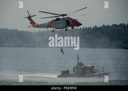 SEATTLE (July 31, 2018) A U.S. Coast Guard MH-60T Jayhawk Helicopter recovers a diver while performing a mock rescue during a search and rescue demonstration over Elliott Bay as part of the 69th annual Seafair Fleet Week. Seafair Fleet Week is an annual celebration of the sea services wherein Sailors, Marines and Coast Guard members from visiting U.S. Navy and Coast Guard ships and ships from Canada make the city a port of call. Stock Photo