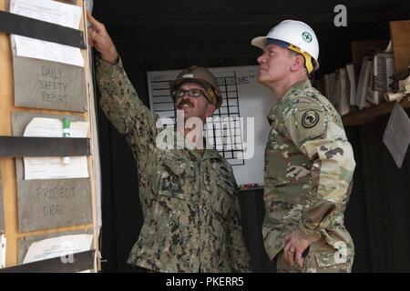 U.S. Navy Builder Petty Officer 1st Class Nathan Fowell, project supervisor, Naval Mobile Construction Battalion 11, Combined Joint Task Force - Horn of Africa, gives U.S. Army Maj. Gen. James Craig, commander, CJTF-HOA, a tour of a construction site for a medical center outside of Ali Oune, Djibouti, July 30, 2018. The completed site will include a maternity ward, a nursery and living quarters for medical staff. Stock Photo