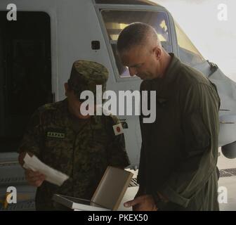 Lieutenant Col. Joshua M. Smith, commanding officer of Marine Medium Tiltrotor Training Squadron-204 with 2nd Marine Aircraft Wing, goes over the schematics of the MV-22 Osprey with Maj. Gen. Yoshiki Adachi, Defense and Military Attaché, Embassy of Japan, on Marine Corps Air Station New River, N.C., Aug. 2, 2018. Adachi is visiting the Marines and Sailors of II Marine Expeditionary Force to continue to build relationships and understand II MEF’s mission and activities in the western hemisphere in regards to its amphibious capabilities and operations. Stock Photo