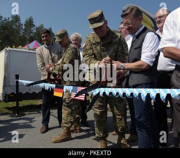 U.S. Army Brig. Gen. Chris LaNeve (left), commanding general of the 7th Army Training Command, and Col. Adam Boyd (center), commander of U.S. Army Garrison Bavaria, cut the ceremonial ribbon alongside German community leaders from around the Grafenwoehr Training Area to open the 60th German/American Volksfest in Grafenwoehr, Germany, Aug. 3, 2018. Stock Photo