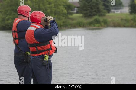 Jerry Hopewell, 788th Civil Engineer Fire Department firefighter, uses binoculars to scan Bass Lake for a reported drowning subject as part of a base exercise at Wright-Patterson Air Force Base, Ohio, July 31, 2018. Divers from the fire department also responded to locate and recover the dummy portraying the victim. Stock Photo