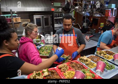 SEATTLE (Aug. 3, 2018) Hospital Corpsman 1st Class Jonathan Faletoi (right), assigned to Naval Hospital Bremerton, prepares meals with his wife, Stephanie, (middle), and sister, Patricia, (left), at Bread of Life Mission during a Seattle Seafair Fleet Week community relations event. Seafair Fleet Week is an annual celebration of the sea services wherein Sailors, Marines and Coast Guard members from visiting U.S. Navy and Coast Guard ships and ships from Canada make the city a port of call. Stock Photo