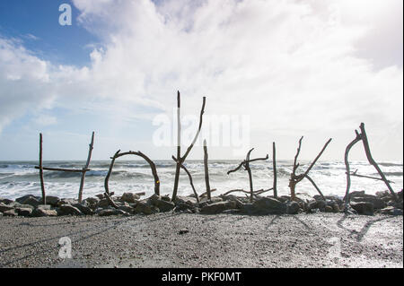 A driftwood sculpture, created from wood washed up on the beach displays the name of a town on Hokitika Beach, South Island, New Zealand. Striking sil Stock Photo