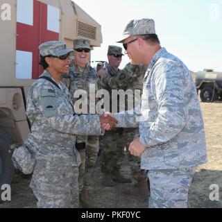 Sgt. 1st Class Cheyanne Mortenson with the 41st Infantry Brigade Combat Team’s 141st Brigade Support Battalion receives a coin from Maj. Gen. Michael E. Stencel, Adjutant General, Oregon, after exceeding her unit’s expectations July 31, 2018 at Camp Roberts, California during the 41st IBCT’s eXportable Combat Training Capability (XCTC) exercise. XCTC is designed to certify platoon proficiency across the brigade in coordination with First Army. “Think about safety, stay focused on what you need to do to do your job and be ready in the event that this nation calls on you,” said Stencel. “There i Stock Photo