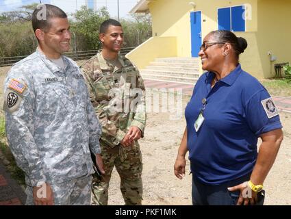 Capt. Signalda Olario (left), a senior leader in the Volunteer Corps Curacao (VKC), greets Capt. J.R. Wiggins (center) and Maj. David Tavares (left), of the Florida Army National Guard (FLARNG). Members from the FLARNG arrived in Curacao to support an information exchange with the VKC to focus on best practices on search and rescue, and medical response tactics, July 30, 2018. Stock Photo