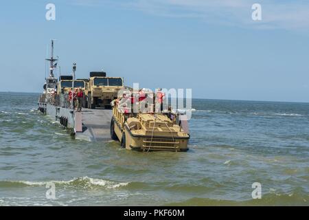 VIRGINIA BEACH, Va. (July 26, 2018) Sailors from Beachmaster Unit (BMU) 2 use a Lighter, Amphibious Resupply, Cargo, Five – ton (LARC – V) to drop off U.S. Army drivers onto an Improved Navy Lighterage System (INLS) Causeway Ferry operated by Amphibious Construction Batallion (ACB) 2 during the Trident Sun 18 exercise onboard Joint Expeditionary Base Little Creek – Fort Story. Trident Sun 18 is a maritime prepositioning force (MPF) operation intended to provide training to reserve component personnel with regards to the in stream offload of military vehicles and equipment. Stock Photo