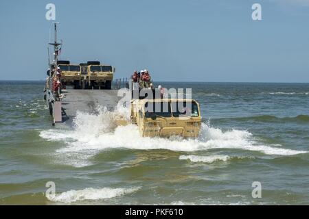 VIRGINIA BEACH, Va. (July 26, 2018) A U.S. Army Heavy Expanded Mobility Tactical Truck disembarks an Improved Navy Lighterage System (INLS) Causeway Ferry operated by Amphibious Construction Battalion (ACB) 2 after stabbing Utah Beach during the Trident Sun 18 exercise onboard Joint Expeditionary Base Little Creek – Fort Story. Trident Sun 18 is a maritime prepositioning force (MPF) operation intended to provide training to reserve component personnel with regards to the in stream offload of military vehicles and equipment. Stock Photo