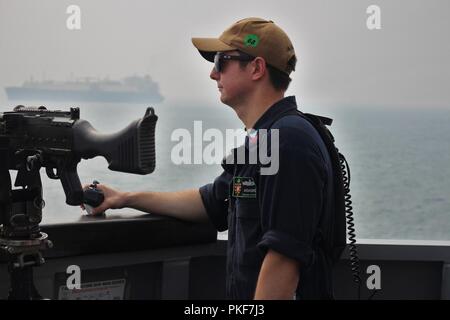 STRAIT OF HORMUZ (August 8, 2018) Information Specialist 1st Class Robert Adams stands watch as the guided-missile destroyer USS The Sullivans (DDG 68) conducts a routine transit through the Strait of Hormuz. The Sullivans is deployed to the U.S. 5th Fleet area of operations in support of naval operations to ensure maritime stability and security in the Central region, connecting the Mediterranean and the Pacific through the western Indian Ocean and three strategic choke points. Stock Photo