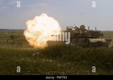 An M1A2 Abrams tank assigned to Comanche Troop, 1st Squadron, 7th Cavalry Regiment, 1st Armored Brigade Combat Team, 1st Cavalry Division, fires during a unit training observation day at the central training area in Várpalota, Hungary, Aug. 3, 2018. Comanche Troop invited the U.S. Ambassador to Hungary David B. Cornstein, mayors from the towns surrounding the training area, Hungarian soldiers and local Hungarian media to view static displays and demonstrations of vehicles, weapons, equipment and capabilities. Stock Photo