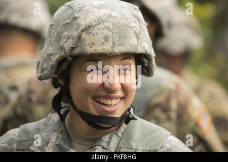 U.S. Army Reserve Spc. Laura Feinschil, assigned to the 367th Military Police Company, from Horsham, Pennsylvania, laughs with fellow soldiers between training events located on Fort McCoy, Wisconsin, Aug. 7, 2018. U.S. Army Reserve MPs were on McCoy, honing basic soldiering and MP specific skills such as detention operations and combat support during Operation Blue Shield. Stock Photo