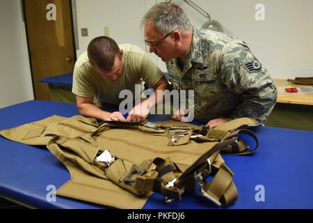 Tech. Sgt. Kurt Mellott and Staff Sgt. Stephen Falker, aircrew flight equipment technicians with the 193rd Special Operations Support Squadron, Middletown, Pennsylvania, Pennsylvania Air National Guard, build a Low-Profile Parachute from scratch Aug. 9, 2018. The new parachutes replaced the old ones, which were originally constructed in the 1980’s. Stock Photo