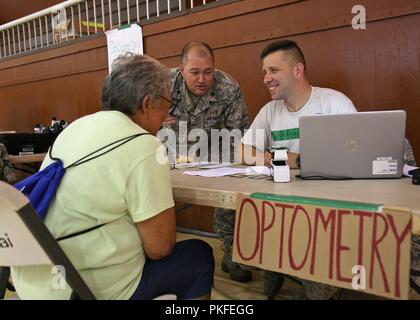 U.S. Air Force Maj. Derek Melton, a optometrist (left) and Tech. Sgt. Michael Atchison a omptometry technician both assigned to the 181st Medical Group, Indiana Air National Guard, check-in in a patient for a eye exam Aug. 11, 2018 at Lanai City, HI. Tropic Care Maui County 2018 provides medical service members and support personnel “hands-on” readiness training to prepare for future deployments while providing direct and lasting benefits to the people of Maui, Molokai, and Lanai, August 11-19. Stock Photo