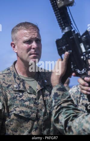 PACIFIC OCEAN – U.S. Marine Lt. Col. Matthew Danner, the battalion commander of Battalion Landing Team 3/1, 13th Marine Expeditionary Unit (MEU), inspects a rifle aboard the Wasp-class amphibious assault ship USS Essex (LHD 2) during a regularly scheduled deployment of Essex Amphibious Ready Group (ARG) and the 13th MEU July 31, 2018. The Essex ARG/MEU team is a strong, flexible, responsive and consistent force capable of maneuver warfare across all domains; it is equipped and scalable to respond to any crisis from humanitarian assistance and disaster relief to contingency operations. Stock Photo