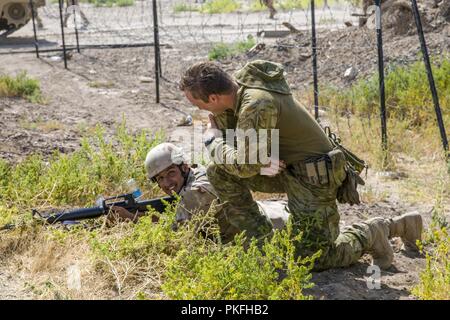 Australian army Cpl. Guy Stein, a Task Group Taji trainer, speaks with an Iraqi soldier assigned to Iraqi army 2nd Battalion, 59th Brigade, during a confirmatory training activity rehearsal at Camp Taji, Iraq, July 29, 2018. Enabled by accelerated successes against ISIS in 2017, Coalition support to our partners is evolving as we assist our partners in providing security that enables stabilization efforts. Stock Photo