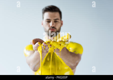 Handsome bearded man showing hands covered in yellow paint isolated on white background Stock Photo