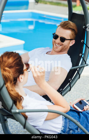 young couple in white t-shirts flirting in front of swimming pool Stock Photo