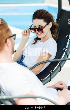 happy young couple in white t-shirts flirting in front of swimming pool Stock Photo
