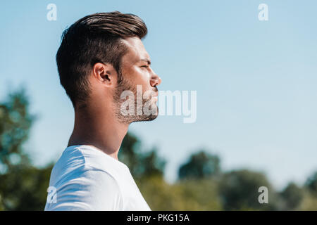 side view of young soldier in white shirt against blue sky Stock Photo