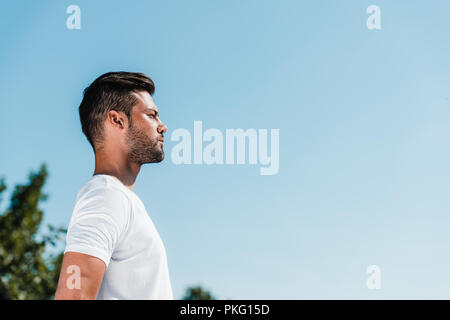 side view of young soldier in white shirt against blue sky Stock Photo