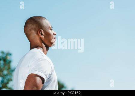 side view of confident african american soldier in white shirt against blue sky Stock Photo
