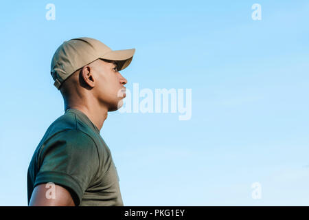 side view of african american soldier in cap against blue sky Stock Photo
