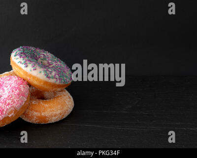 A pile of three ring donuts against a black background Stock Photo